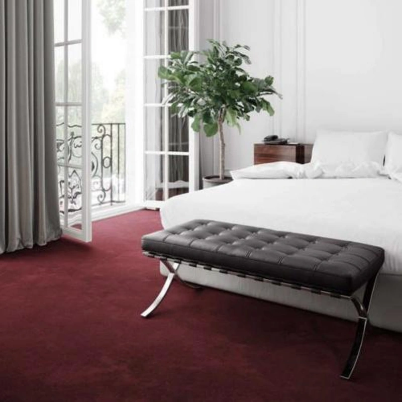 Sophisticated wine-red bedroom carpet with a modern black leather bench.