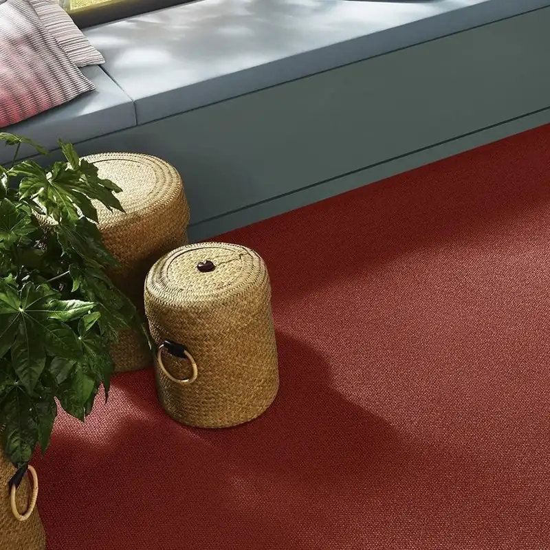 Terracotta red textured carpet with woven storage baskets