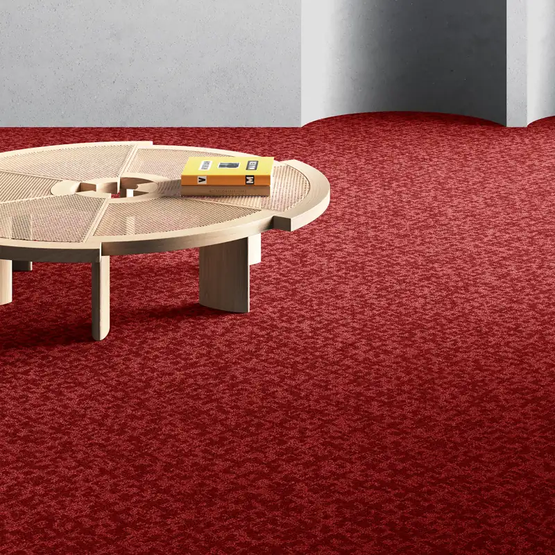Textured ruby red wall-to-wall carpet with a modern circular coffee table.